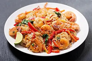 Stir Prints: plate of Stir fried noodles with shrimps and vegetables on dark background