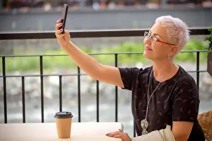 Blouse Prints: pleasant mature woman is taking a selfie at the cafe