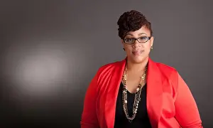 Skirt Prints: Plus size black woman wearing glasses in a smart business outfit on a neutral grey background