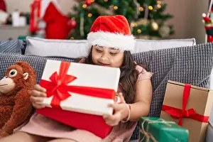 Apartment Prints: Plus size hispanic girl unpacking gift sitting on sofa by christmas tree at home