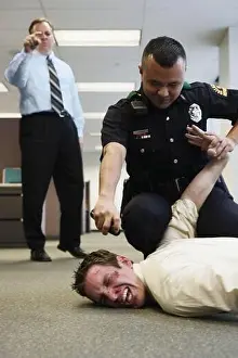 Bending Prints: Police officer holding beat up businessman on floor in office