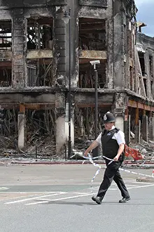 Riot Prints: Policeman walking past damage caused by riot and looting in Tottenham