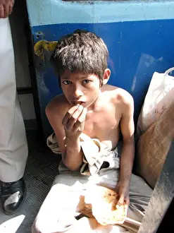 Hunger Prints: A poor hungry boy eating a stale roti (bread) in an Indian train