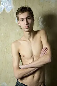 Lean Prints: portait of young bare serious man with pirsing in eyebrow standing opposite the wall