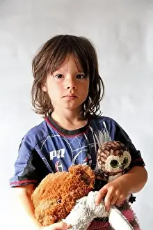 Pyjamas Prints: Portrait of 8 year old boy, with long hair wearing his pyjamas and holding some soft toys