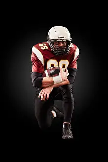 Bald Prints: Portrait of American football player holding a ball with both his hands