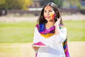 Indian People Prints: Portrait of attractive pretty young Indian woman wearing white cloths holding powder color plate celebrating holi