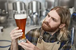 Maker Prints: Portrait of bearded brewmaster holding beer glass while inspecting quality of production at brewing factory