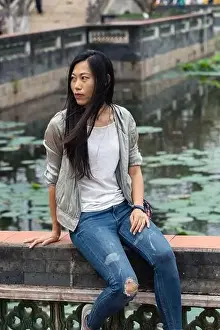 Portrait of beautiful Asian girl hanging out in a Japanese garden pond with some traditional architecture in
