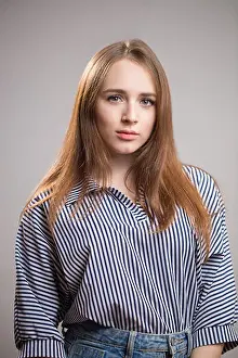 Portrait of a beautiful redhead woman wearing a striped blouse and looking at the camera on a gray background
