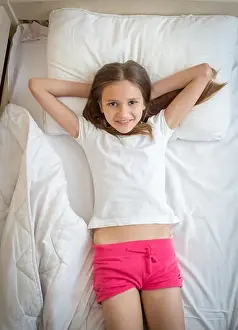 Pajamas Prints: Portrait of beautiful smiling girl in pajamas lying on bed and looking up