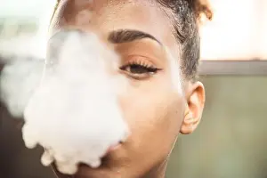 Dense Prints: Portrait of a black girl with smoke coming out of her mouth that covers half her face