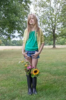 Natural World Prints: Portrait of blond girl standing on a meadow with bunches of flowers in her rubber boots