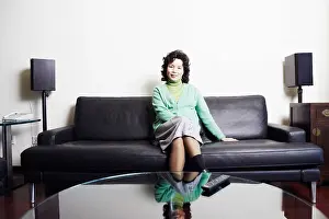 Remote Control Prints: Portrait of a businesswoman sitting on a couch smiling