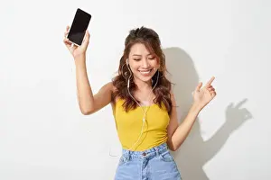 Portrait of a cheerful beautiful girl showing or presenting mobile phone application and pointing finger to sky