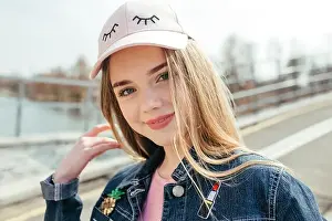 Portrait closeup beautiful young girl in pink hat in city street
