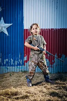 Aspirations Prints: Portrait of confident girl holding rifle while standing on field