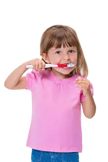 Bedtime Prints: Portrait of cute little girl 3 year old in pink t-shirt brushing her teeth isolated on white background