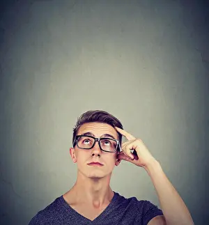 Contemplate Prints: Portrait doubtful thinking young man bewildered scratching his head seeks a solution looking up isolated on wall