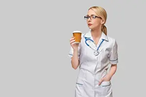 Take Away Prints: Portrait of a female doctor holding paper cup of coffee standing over grey background