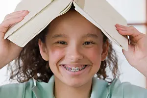 Curly Hair Prints: Portrait of a girl putting book on her head and smiling