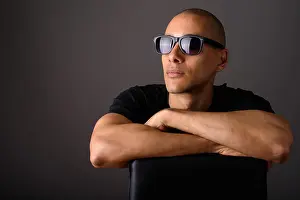 Bald Prints: Portrait of handsome bald man sitting on chair and wearing sunglasses