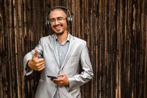 Business Person Prints: Portrait of happy businessman with headphones. Wooden background