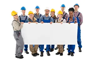 Tradesman Prints: Portrait of happy construction workers holding blank billboard against white background
