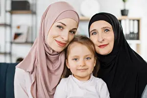 Grandma Prints: Portrait of happy three generations of muslim women hug and cuddle posing at home together