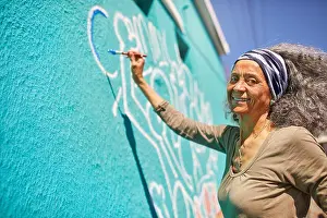 Weekend Activities Prints: Portrait happy senior female volunteer painting on sunny wall