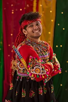 Gujarat Prints: portrait of happy young man in kedia and dhoti holding dandiyas during Navratri celebrations