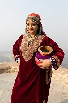 Garments Prints: Portrait of an Indian woman wearing ethnic Kashmiri dress and carrying a mud pot as she poses for a tourist photo