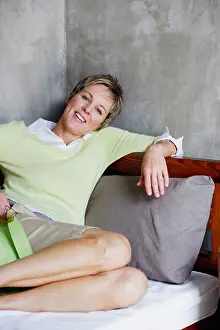 Leisurely Prints: Portrait of a mature woman reclining on the bed and smiling