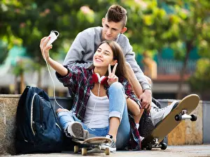 Teens Prints: Portrait of smiling boy and girl teens posing at mobile phone for selfie