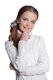 Portrait of smiling little girl wearing warm sweater on white background