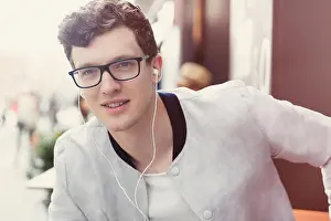 Youth Culture Prints: Portrait smiling man with eyeglasses listening to music on headphones