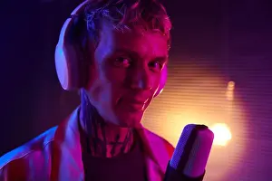 Rapper Prints: Portrait of smiling young man wearing headphones when singing in mike