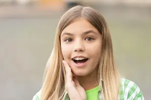 Tween Prints: Portrait of tween girl with surprised face holding hand on cheek blurry outdoors