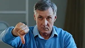 Disgust Prints: Portrait of upset angry sad elderly man looking at camera disgruntled serious mature old grandpa showing dislike thumbs