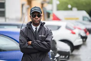Folded Prints: Portrait Of Young African Male Security Guard In Uniform Standing Arms Crossed On Street