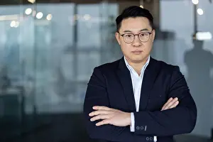 Crossed Prints: Portrait of a young Asian male businessman standing inside an office space in a suit and glasses