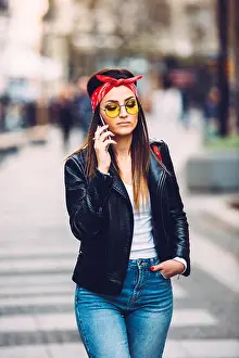 Portrait of young beautiful trendy girl in stylish sunglasses using smart phone
