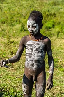 Portrait of young Hamer tribe boy with necklaces and impressive body painting, Omo Valley, Southern Ethiopia