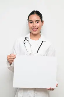 Practitioner Prints: Portrait of a young Thai female doctor in uniform holding a blank medical placard for healthcare promotion