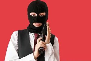 Unrecognizable Prints: Portrait of young woman in balaclava with gun against red background