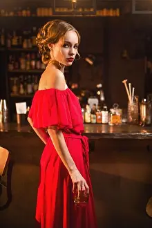 Flirt Prints: Portrait of young woman in red dress standing at the bar counter