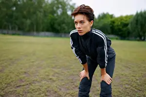 Bending Prints: Portrait of young woman standing with hands on knees during sports training