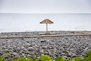 Madeira Island Prints: Praia dos Pescadores beach, composed of basalt pebbles and black sand with straw umbrellas and wooden decks