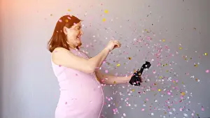 Parenting Prints: Pregnant woman celebrating baby shower with pink confetti