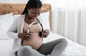 Belly Prints: Pregnant Woman Holding Headphones Near Belly, Playing Melody To Baby In Womb